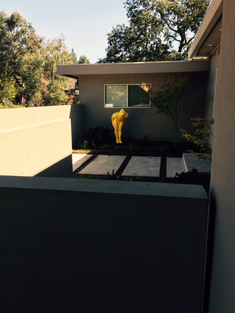 Fiberglass bowing man statue in red and yellow